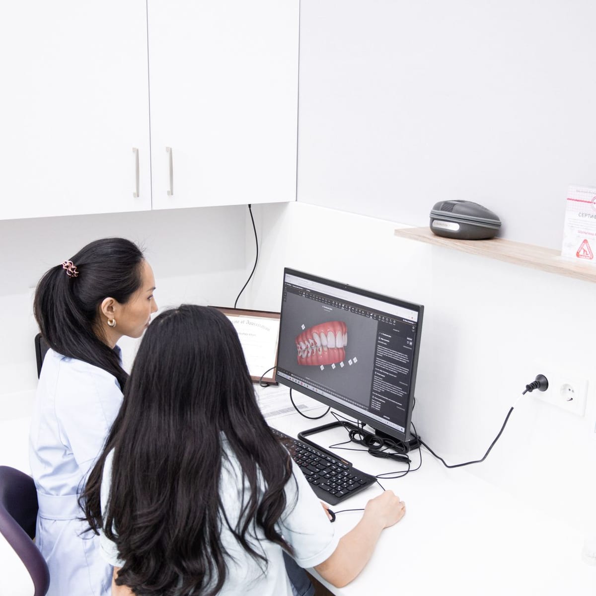 Two clinicians reviewing a 3D model of a smile on a monitor